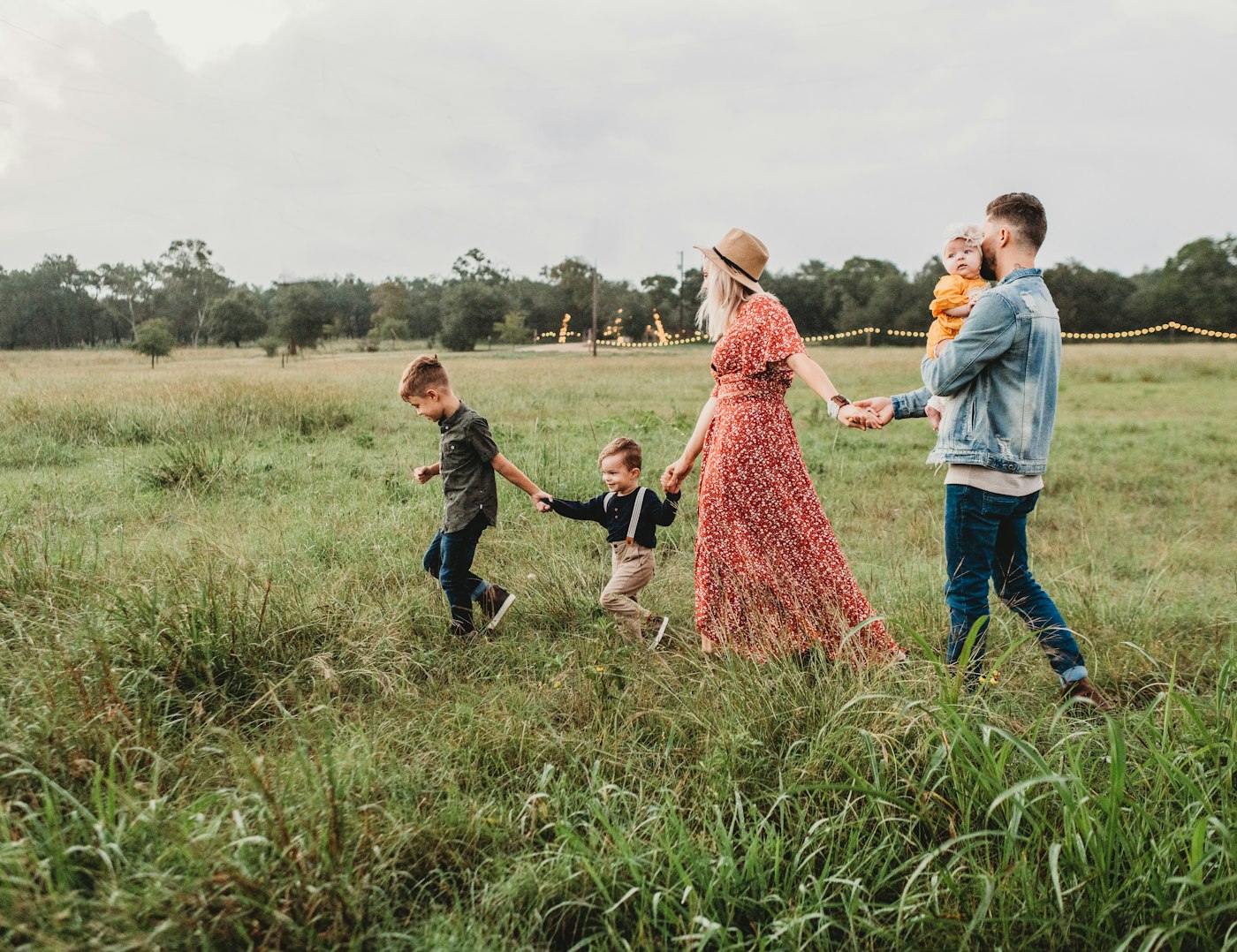 Família caminhando de mãos dadas em um campo verde